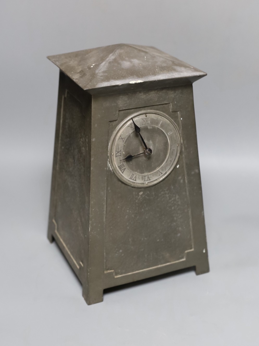 An Art Nouveau Liberty style hammered pewter mantel timepiece, Lenzkirch movement with key, 28 cms high.